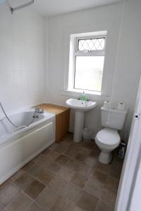 uma casa de banho com uma banheira, um WC e um lavatório. em Ayrshire cottage em Kilmarnock