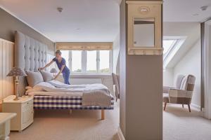 a man is making a bed in a bedroom at Gilleleje Badehotel in Gilleleje