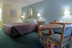 a hotel room with a bed and a table and chairs at Americas Best Value Inn Florida Turnpike & I-95 in Fort Pierce