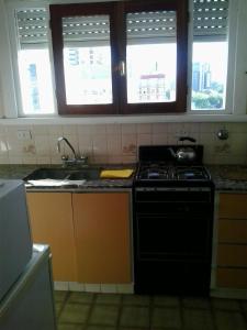 a kitchen with a stove and a sink and windows at Panoramico Playa Grande -Solo Familias in Mar del Plata