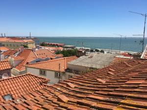 uma vista sobre os telhados de uma cidade com o oceano em Typical river view cosy and central em Lisboa