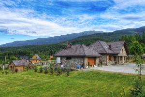 a house in a field with mountains in the background at Babie Zacisze in Zawoja