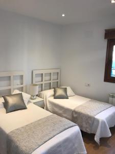 two beds in a room with white walls at Apartamento Toledo Centro in Toledo