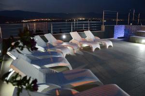 a row of white chairs on a balcony at night at Apartments Exclusive Palace in Trogir