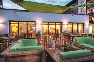 a restaurant with green chairs and tables and windows at Johannesbad Hotel Königshof in Bad Füssing