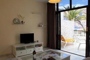 sala de estar con TV de pantalla plana y mesa en House Oasis Raj by Holiday World, en Santiago del Teide