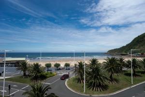 a view of a beach with palm trees and the ocean at San Diego - Iberorent Apartments in San Sebastián