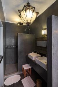 La salle de bains est pourvue de 2 lavabos et d'un grand lustre. dans l'établissement Riad Alegria, à Marrakech