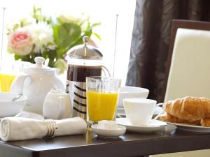 a breakfast table with a glass of orange juice and croissants at Strozzi Palace Suites by Mansley in Cheltenham