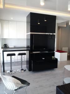 kuchnia z czarnymi szafkami i stołkami barowymi w obiekcie Apartament na Złotej w Kielcach +13 zdjęć