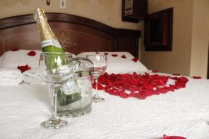 Una botella de champán y dos copas en una cama con rosas. en Motel Piramides De Cristal, en Bogotá