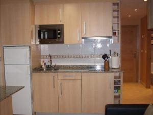 een keuken met houten kasten en een witte koelkast bij Marina Nova in Cedeira