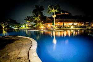 Hotel do Bosque ECO Resort في انغرا دوس ريس: مسبح بالليل فيه نخل ومبنى