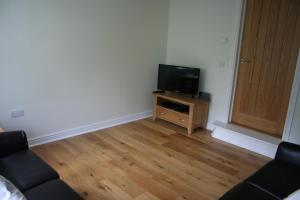 a living room with a tv and a wooden floor at Highlands Apartment 3 in Shanklin