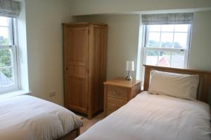 a bedroom with two beds and a dresser and two windows at Highlands Apartment 3 in Shanklin