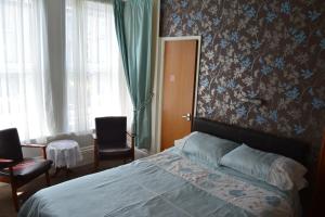 um quarto com uma cama e 2 cadeiras em The Sefton Hotel em Bridlington