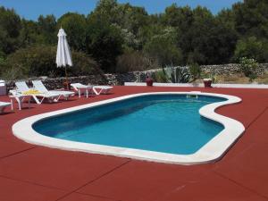 a swimming pool with chairs and an umbrella at Agroturisme Binisaid NOU in Cala Galdana
