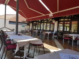 ein Restaurant mit weißen Tischen, Stühlen und roten Sonnenschirmen in der Unterkunft Mobile Homes Seashell Jezera in Jezera