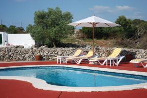 a pool with chairs and a table and an umbrella at Agroturisme Binisaid NOU in Cala Galdana