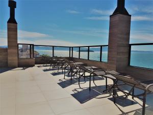 a row of chairs on a balcony with the ocean at Fragata Apart Hotel in Florianópolis