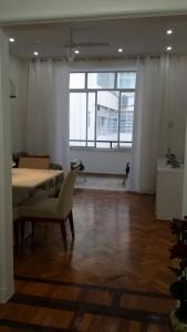 Habitación con mesa, sillas y ventana grande. en Edificio Franco Werneck, en Río de Janeiro