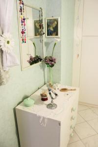 d'un meuble blanc avec un miroir et des fleurs. dans l'établissement Lagomare Puccini, à Torre del Lago Puccini
