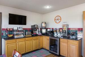 a kitchen with wooden cabinets and a tv on the wall at Howard Johnson by Wyndham Wichita Airport in Wichita