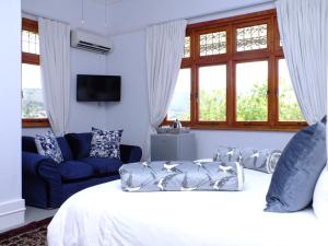 1 dormitorio con cama, sofá y ventanas en Villa Zeezicht, en Ciudad del Cabo