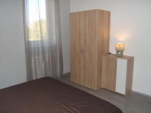 ジェールにあるKultúrház Apartmanのベッドルーム1室(ベッド1台付)、木製キャビネットが備わります。