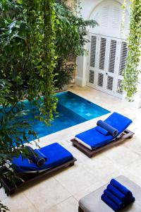 
a row of blue chairs sitting in front of a blue pool at Hotel Casa Don Sancho By Mustique in Cartagena de Indias
