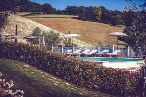 a swimming pool with umbrellas and lounge chairs at Agriturismo Casal San Sergio in Fossombrone