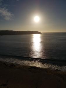 una puesta de sol sobre el océano con el sol sobre el agua en Apartmento La Herradura, en Coquimbo