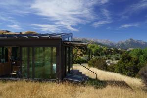 uma casa de vidro numa colina com montanhas ao fundo em Kahutara PurePod em Kaikoura