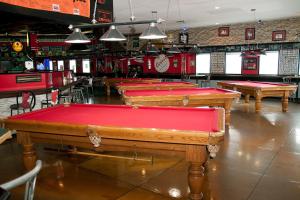 El Lobo Motel في Cold Lake: صف من طاولات البلياردو في بار ذو غطاء احمر