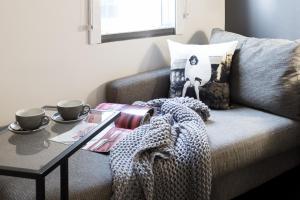 ibis Sydney Barangaroo في سيدني: غرفة معيشة مع أريكة مع طاولة و كوبين