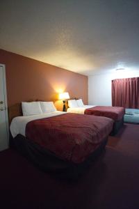 a hotel room with two beds and a lamp at Econo Lodge Elk City in Elk City