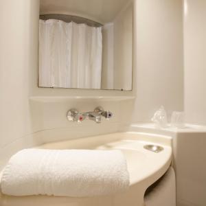 a white bathroom with a sink and a mirror at Premiere Classe Sete - Balaruc in Balaruc-le-Vieux