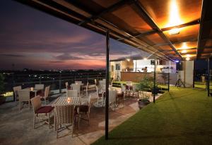 a rooftop patio with tables and chairs at night at Yellow Star Gejayan Hotel in Yogyakarta