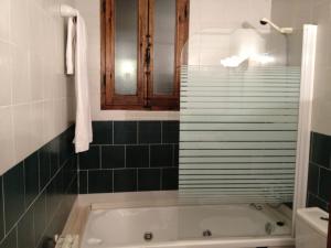 uma casa de banho com banheira e azulejos verdes em Hostatgeria Sant Jaume em Coratxar