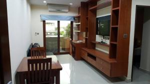 ein Wohnzimmer mit einem TV, einem Schreibtisch und Stühlen in der Unterkunft The Supara in Bangkok