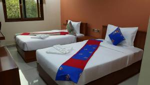 two beds in a hotel room with red white and blue sheets at The Supara in Bangkok