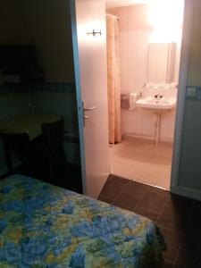 Schlafzimmer mit einem Bad mit einem Bett und einem Waschbecken in der Unterkunft Hôtel l'Eden in Brix