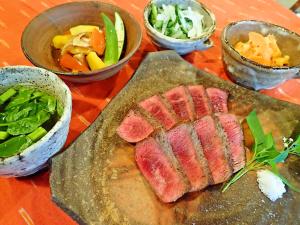 einen Tisch mit einem Teller Fleisch und Schalen von Gemüse in der Unterkunft Nata Beach Villa in Ishigaki-jima
