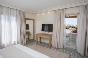 a hotel room with a bed and a television and curtains at Porto Naxos in Naxos Chora