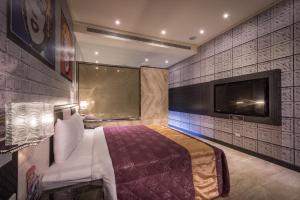 a bedroom with a bed and a flat screen tv at OUGE Boutique Motel - Pingtung in Jiuru