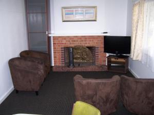 sala de estar con chimenea, sillas y TV en Restawile Motel, en Busselton