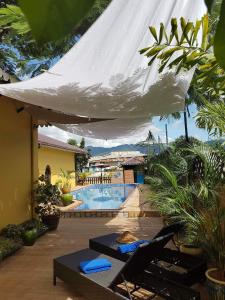 a patio with a swimming pool and a white umbrella at Thanakha Inle Hotel in Nyaungshwe Township