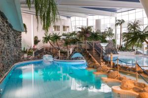 una piscina en un hotel con sillas y un puente en Holiday Club Kuusamon Tropiikki Superior Apartments, en Kuusamo
