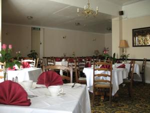una sala da pranzo con tavoli e sedie bianchi e tovaglioli rossi di Michaelson House Hotel a Barrow in Furness