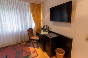 a hotel room with a desk and a television on the wall at Hotel Sauerbrey in Osterode